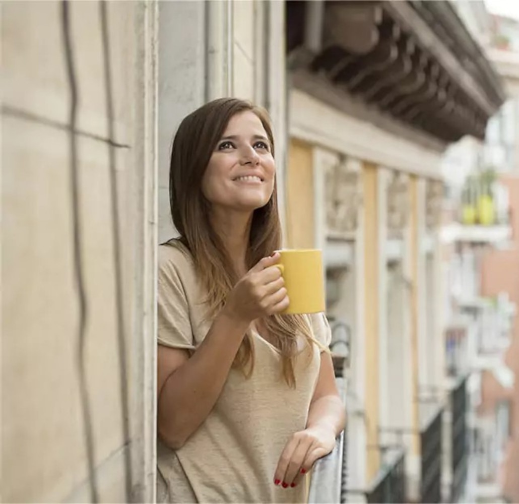 Mujer en el balcón tomando cappuccino