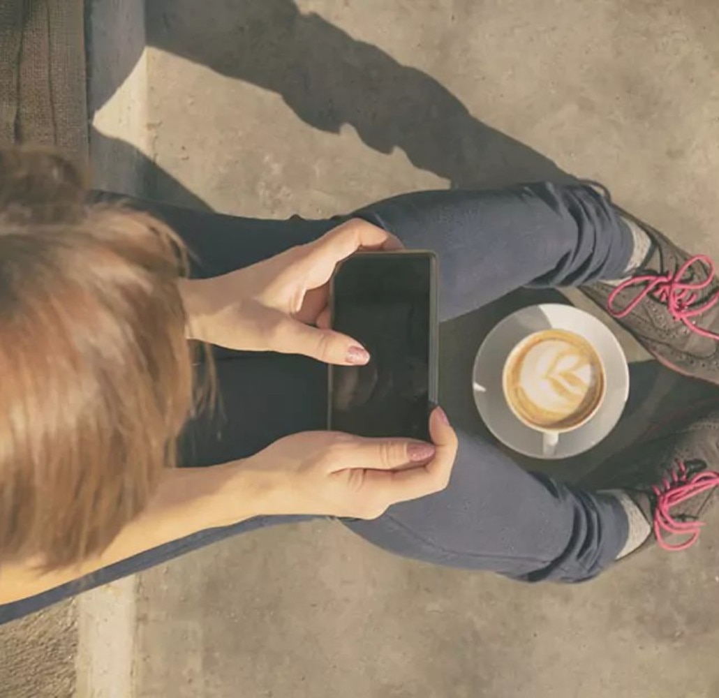 Mujer tomando una taza de cappuccino sentada en el portal